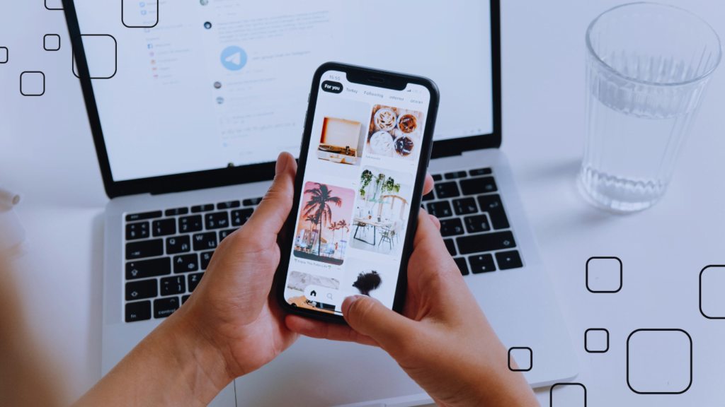 smartphone w dłoniach na tle laptopa